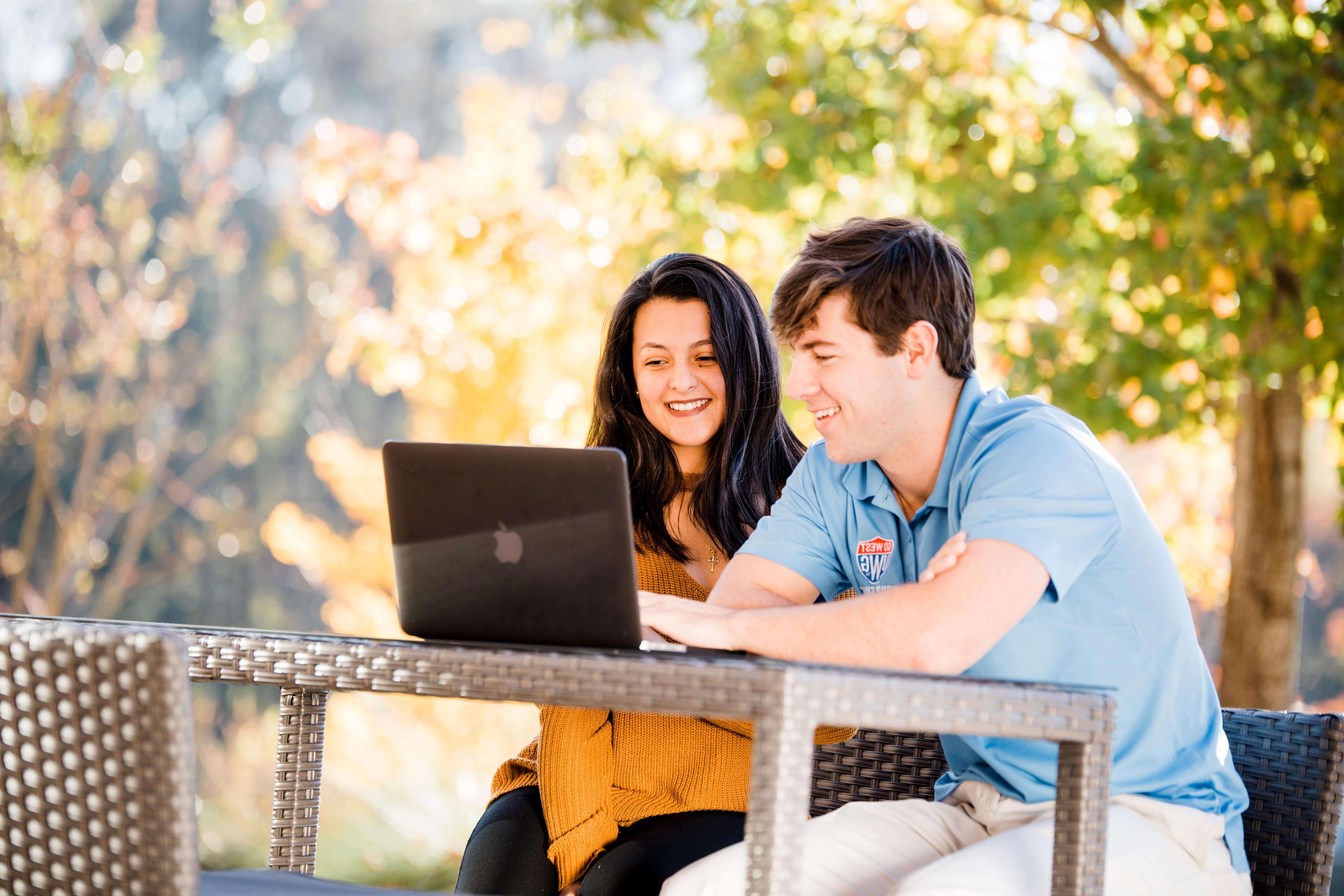 Students sitting at an outside table studying.