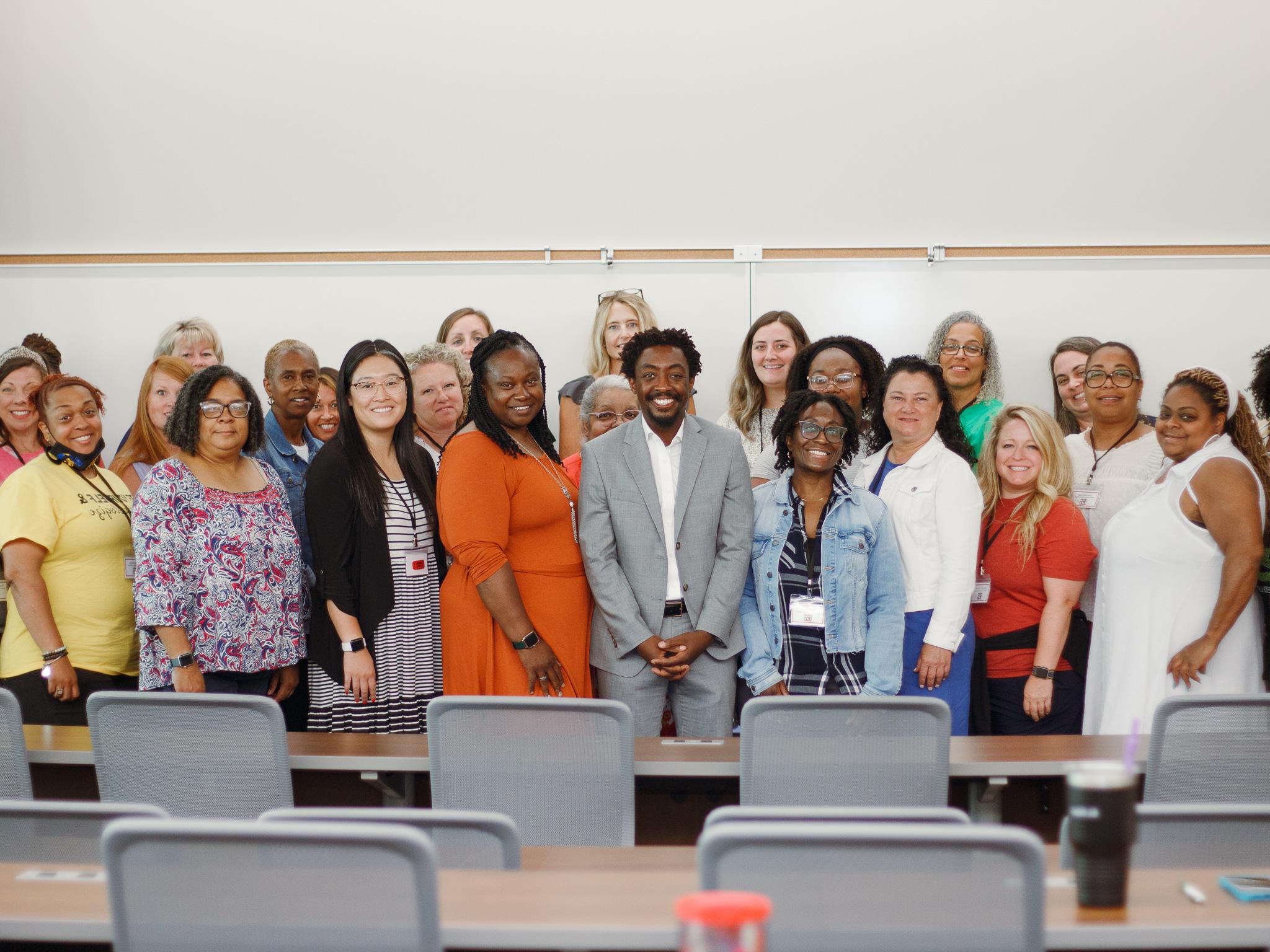 Group of teachers standing together for a group photo in front of a classroom.